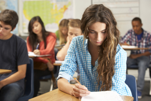 female-pupil-studying-at-desk-in-classroom